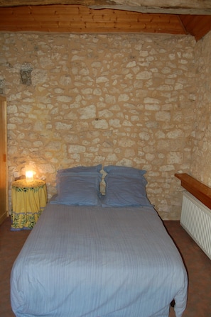 The upstairs bedroom is set with beams and stone walls