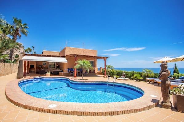 Private pool with sea views surrounded by shaded terraces and gardens.