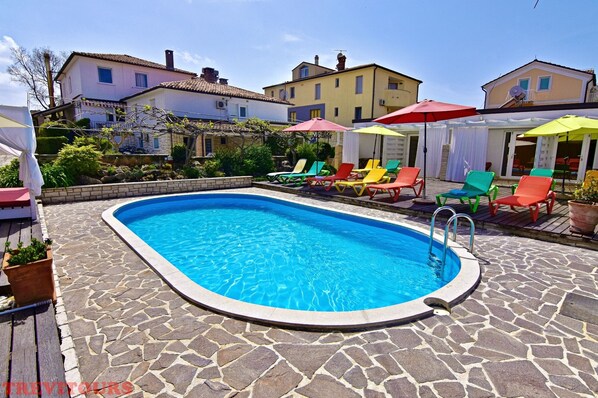 Outdoor pool with sun loungers and umbrellas available for use