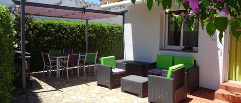 terrasse sud, salon extérieur avec store, coin repas et pergola, plancha