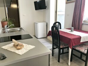 L'ingresso nella zona giorno con TV, frigorifero e tavolo da pranzo.