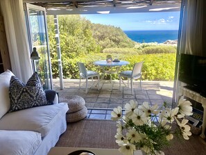 Sea facing patio off living area with loungers and barbecue