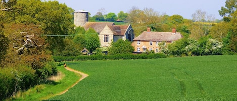 View towards cottage and church from fields at front.