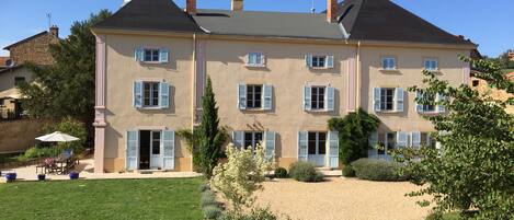 South facade with its french doors, terrace,  lavendar wisteria and fruit trees.