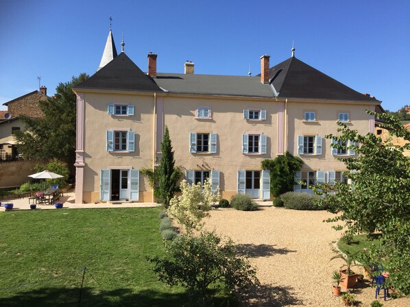 South facade with its french doors, terrace,  lavendar wisteria and fruit trees.