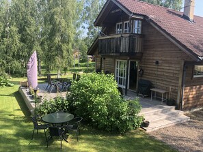 The wooden deck with patio furniture and charcoal barbecue. 
