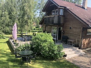 The wooden deck with patio furniture and charcoal barbecue. 