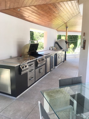 The outdoor kitchen has gas bbq & hob, wood-fired pizza oven, fridge & sink