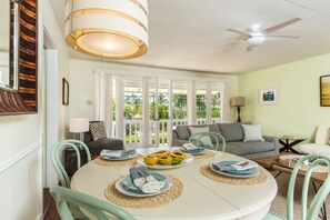 Gather around the dining table in Lanikai Cottage's main house, where natural light and cozy decor set the perfect ambiance.