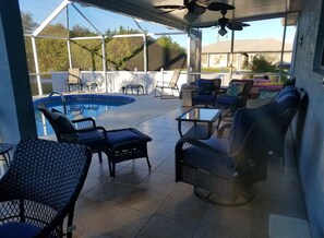 Relax in this peaceful lanai and heated pool with new comfy wicker furniture .