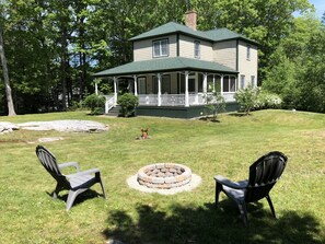 The fire pit and front corner of the house with the screened in porch beyond.