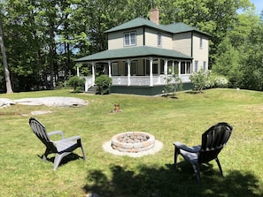 The fire pit and front corner of the house with the screened in porch beyond.