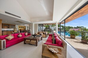 Indoor living area with sofas, air conditioning and direct access to pool.