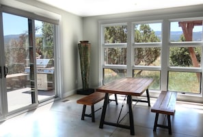 Corner of living room, showing dining area, wood sculpture, grill on porch.