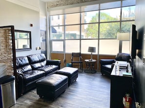 Electronic remote shade on huge window. Italian leather furniture. Urban decor.
