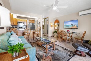 This open-concept living area features tropical décor, a comfortable sofa, and a spacious glass coffee table, creating the perfect setting for relaxation.