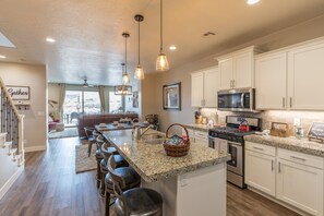 Kitchen View Into Living Room - The kitchen is fully stocked with all the dishes, cookware, baking pans, and cutlery you will need for meal preparations and includes stainless steel appliances and granite counter tops.