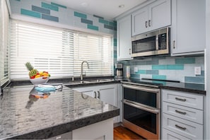 Remodeled kitchen with all new appliances, stone counters and tile backsplash.