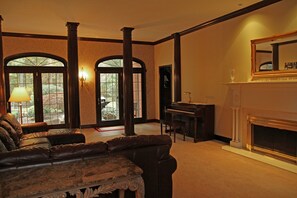 Living room with views of the front and back yards, piano, organ, and fireplace.