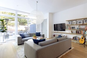 Living room with 60" HDTV connects to large back porch and fenced backyard.