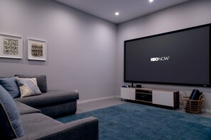 Media room has 10'-diagonal projector screen and sectional sofa with pullout bed