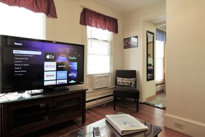 Large (55" or larger) flat screen smart Roku TV in the living room.  Just bring your streaming apps to watch all your favorite sports and shows!