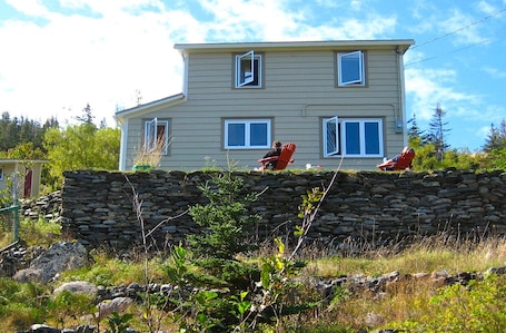House from below, sits atop old stone wall, surrounded by sun all day long.