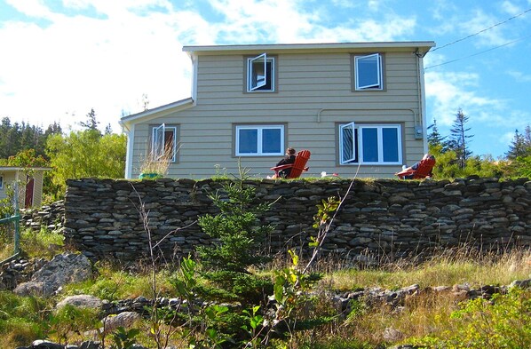House from below, sits atop old stone wall, surrounded by sun all day long.