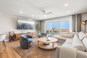 Newly furnished living area with ample seating, large flat screen television, air conditioning, and access to patio just off of the beautiful, open kitchen.