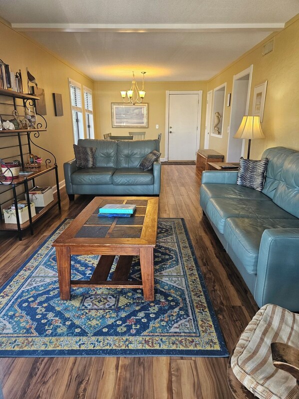 Living room with a smart TV, leather couches, and private balcony.