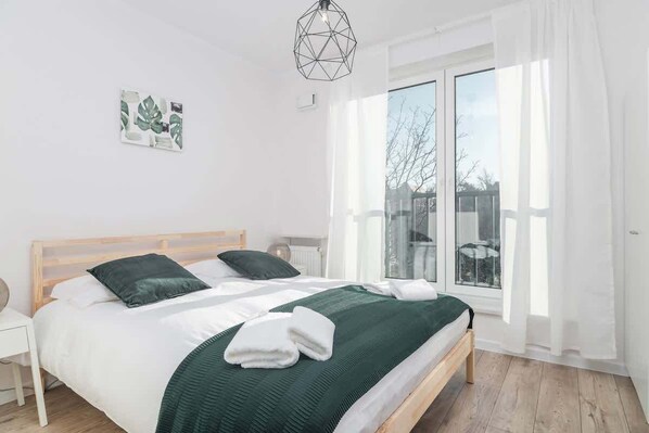 A bright, cosy bedroom with a double wooden bed with a green bedspread.