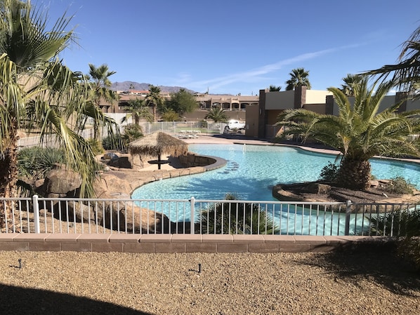 Resort pool off the back patio with a swim up island in the background. 