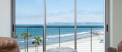 Sliding glass windows open to waves and ocean breeze