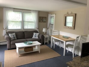 Cozy living room with a pull out couch, AC and a dining table.