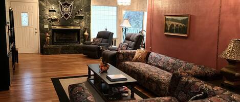 Large open living room with rock wall and adjoining formal dining room and porch