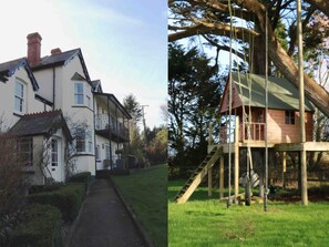 Side entrance to the house with tree house in garden.
