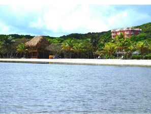 View of condo building, beach & palapa from water