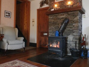 Common area with two recliners,  large screen TV & wood burning stove.