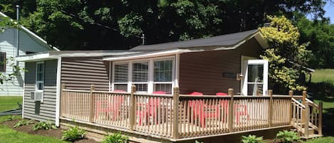 Lake house with wrap-around front deck and adirondack chairs for lounging.