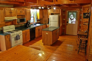 Kitchen equipped with dishes, cookware, appliances, and an island for serving!