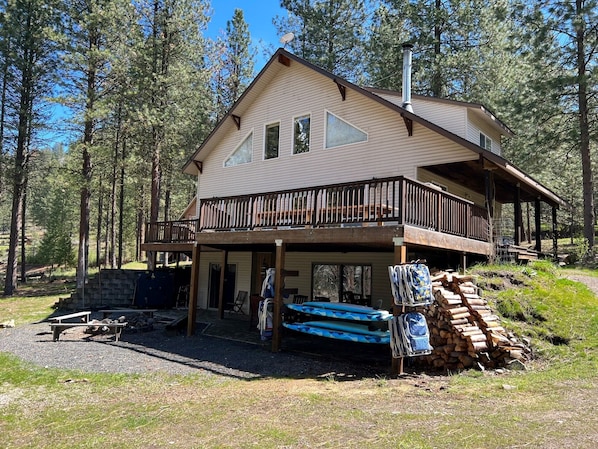 Waterfront side of house with provided beach chairs, paddle board and fire pit