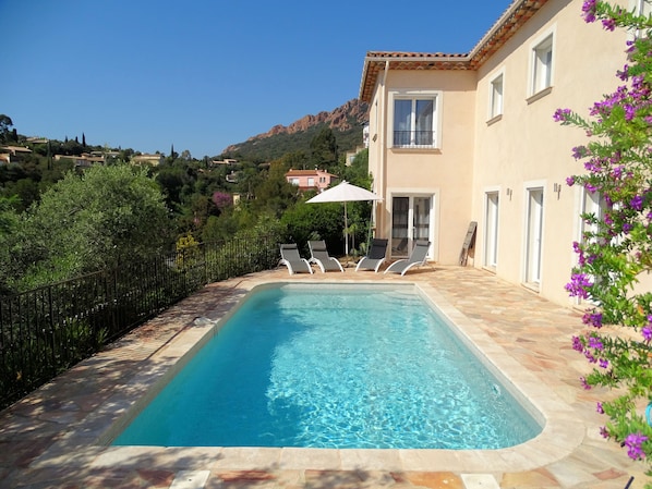 Grande piscine ensoleillée avec bains de soleil, parasol et coin détente