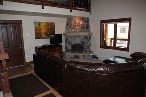 Living room - 'L' shaped leather couch, flat screen TV and river rock fireplace