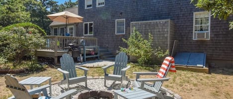 fire pit with 4 Adirondack chairs at rear of home