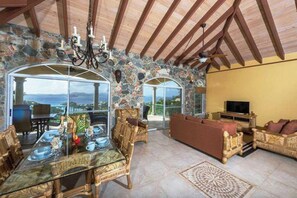 The handsome great room is a classic beauty with arched stone walls, a cathedral ceiling, tiled floors and fabulous views