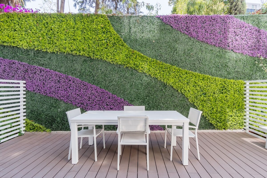 melhor airbnb cidade do méxico condesa e roma norte |  Mesa e cadeiras brancas em um pequeno jardim urbano ao ar livre com parede com grama e flores roxas