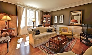 Sunny formal living room with wood burning fireplace. Sofa is white, not tan