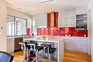 Cook up a feast in the modern, fully equipped kitchen with bold red splashbacks, stainless steel appliances, and a central island with stylish bar seating.