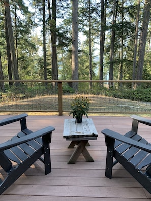 Large front deck facing mud bay water view through the trees, Adirondack chairs