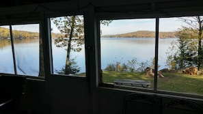 in center of screened porch looking east on lawn, picnic table and lake. 